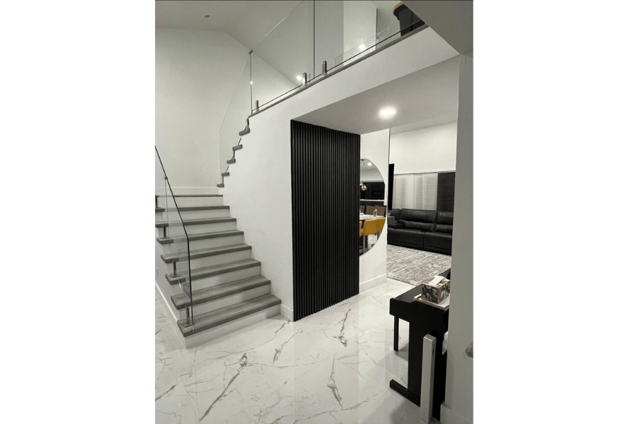 Open staircase with tempered glass railing and black vertical slat feature by Guardian Shield Windows & Doors