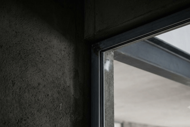 Structural steel frame and concrete junction showing architectural planning constraints for custom glass.